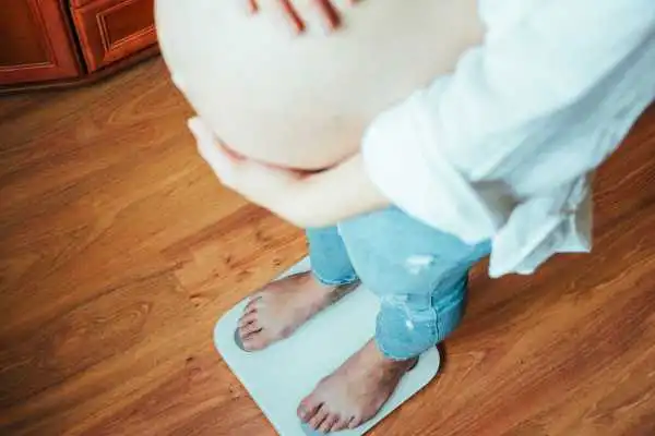 Image of woman weighing herself and experiencing weight gain through pregnancy Southsea